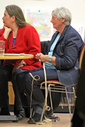 Auf dem Bildausschnitt sieht man Frau Heike Herrmann-Hofstetter
  und Frau Ruth Wunsch whrend der Lesung des Buches Blinde-Schnheit
  auf der Leipziger Buchmesse 2010. Die beiden Damen sitzen
  nebeneinander an einem Tisch.
  Frau Wunsch, deren Krper nach links ausgerichtet ist, sitzt auf
  einem Stuhl am rechten Tischende, sodass der Betrachter sie von der
  Seite sehen kann. Sie ist eine flotte ltere Dame mit weiem
  Kurzhaarschnitt. Sie trgt einen dunkelblauen Jeansanzug, aus der
  Jacke schimmert ein hellblaues T-Shirt. Lssig sitzt sie mit
  berkreuzten Fen da. Sie wirkt sehr konzentriert, denn sie wartet
  gerade auf ihren Einsatz als Vortragende.
  Noch lauscht Frau Herrmann aber ganz entspannt ihrer anderen Sitznachbarin, die
  mittig am Tisch sitzt, hier im Bildausschnitt aber nicht zu sehen
  ist. Sie wendet dieser ihren Kopf zu. Ihr langes mittelblondes Haar
  hat sie hinter die Ohren geklemmt, sodass es sanft auf ihren Rcken
  fliet. Bekleidet ist sie mit dunkler Jeans und einem eleganten
  roten Jackett, aus dem ein glnzend blaues Seidenhemd hervorlugt.
  Zur gleichen Zeit ist Frau Wunsch vollkommen auf sich konzentriert.
  Offensichtlich macht sie sich bereit fr ihre Lesung. So hlt sie
  schon den Anfang des Textstreifens mit Brailleschrift (der
  Punktschrift, mit deren Hilfe sie Texte mit dem Tastsinn ihrer Finger
  erlesen kann) in den Hnden. Sehr sensibel ertastet sie mit den
  Fingerkuppen der rechten Hand bereits die ersten Wrter. Der
  lange Papierstreifen fllt wie eine Girlande locker auf den Boden, wo
  das Papier sich in Ringen sammelt, whrend das Ende der Papierschlange
  leicht gekruselt ber ihrem linken Bein liegt. Gleich beginnt ihr
  Vortrag und dann wird Frau Wunsch die lange Papierschlange sanft
  abtastend durch ihre Hnde gleiten lassen und ihren persnlichen Text
  zum Thema Schnheit dem interessierten Publikum vorlesen.